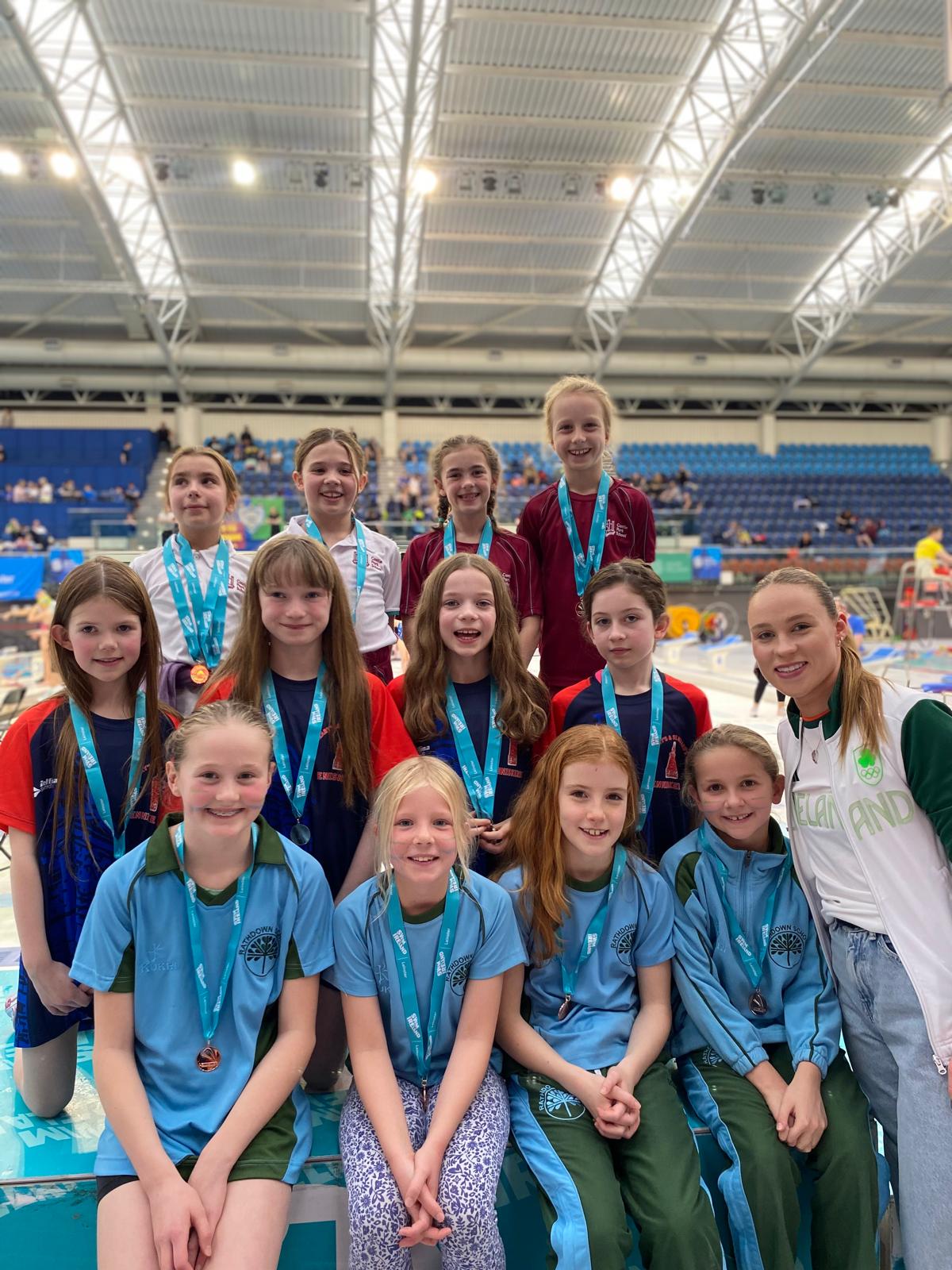 Group shot of swimmers with medals on a podium