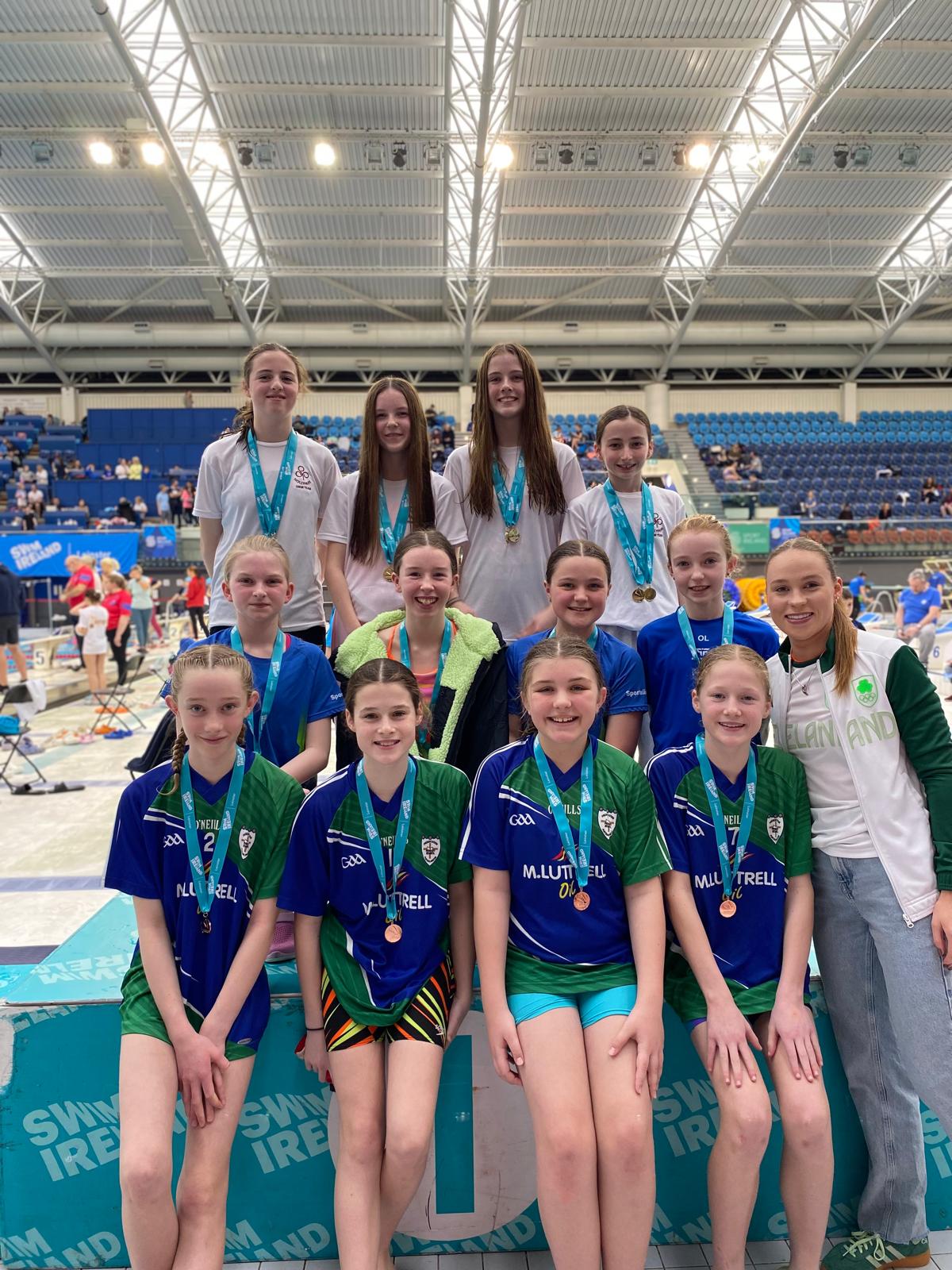 Group shot of swimmers with medals on a podium